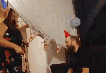 a man wearing a red party hat is kneeling down