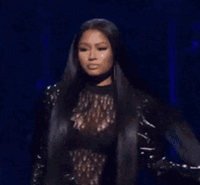 a woman with long black hair is standing on a stage in front of a blue light .