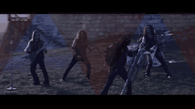 a group of men playing guitars and drums in front of a brick wall
