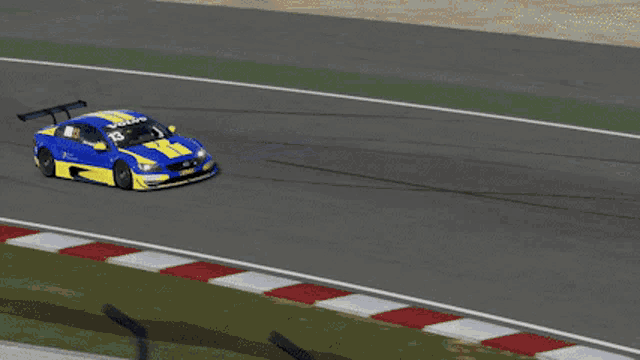 a blue and yellow race car is driving down a road