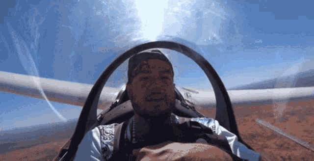 a man with a tattoo on his face is sitting in the cockpit of an airplane
