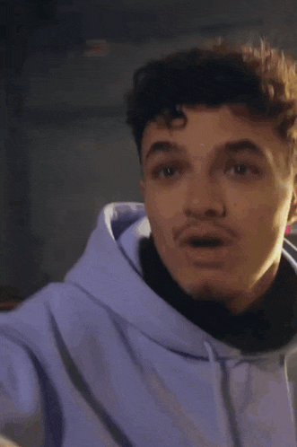 a young man in a purple hoodie is sitting in a chair