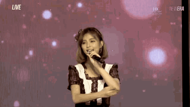a woman singing into a microphone with the word live on the bottom right