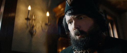 a man with a beard is wearing a black hat with a triangle on it