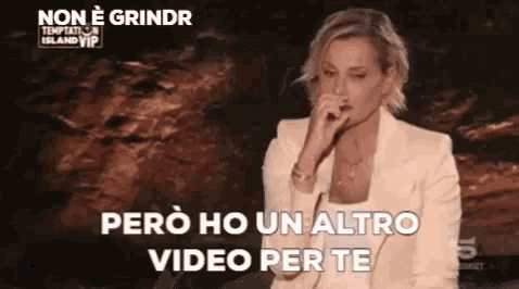a woman in a white suit is singing into a microphone while talking into it .