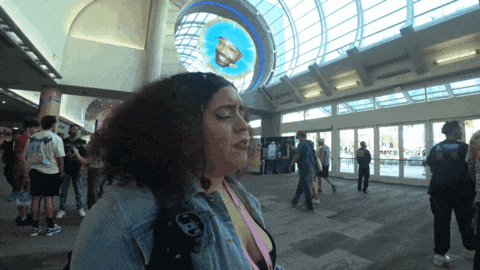a woman in a denim jacket stands in front of a large stained glass window