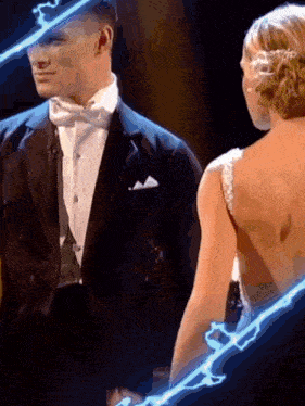 a man in a tuxedo is standing next to a woman in a dress on a stage .