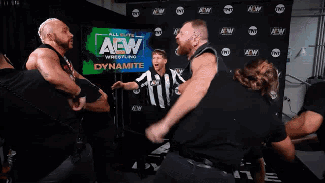 a group of wrestlers are standing in front of a wall that says aew wrestling dynamite