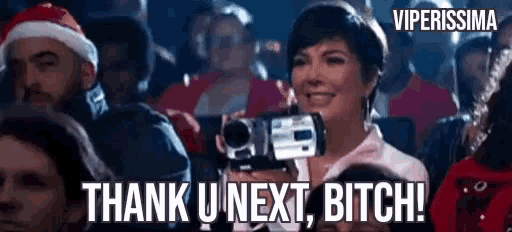 a woman is holding a video camera in a crowd and saying thank u next bitch .