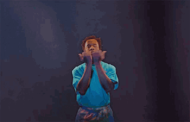 a man in a blue shirt is standing in the dark