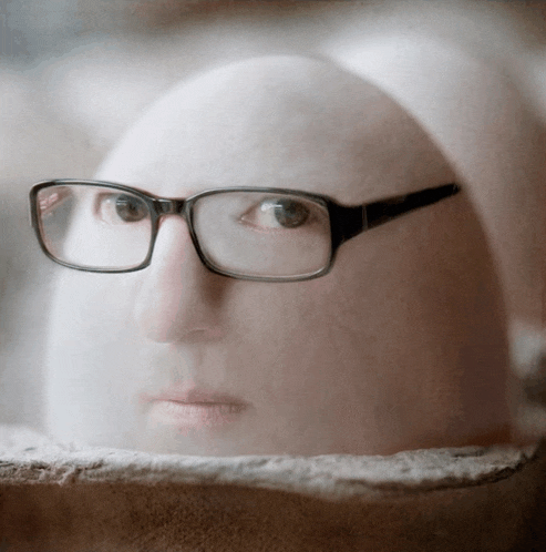 a person wearing glasses is looking out of a hole in the wall