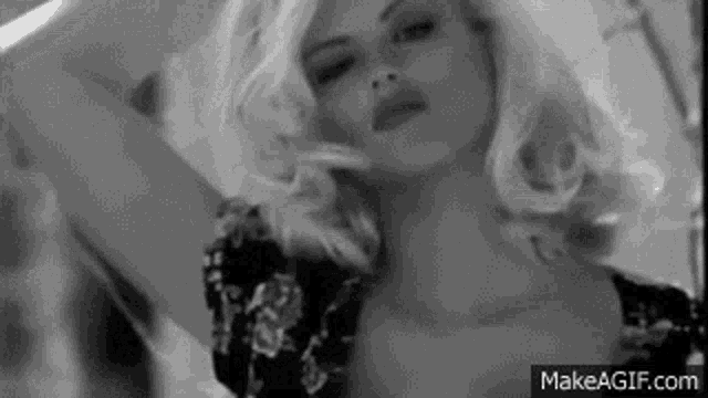 a black and white photo of a woman with blonde hair in a floral dress .