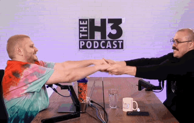 two men shake hands in front of a sign that says " the h3 podcast "