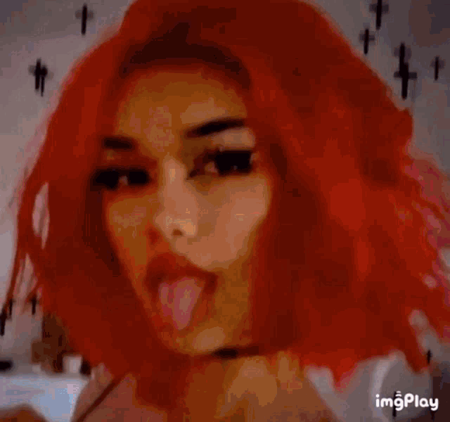 a person with red hair is drinking from a bottle while laying on their back .