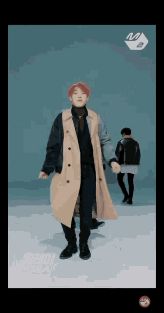 a man in a trench coat is dancing with another man