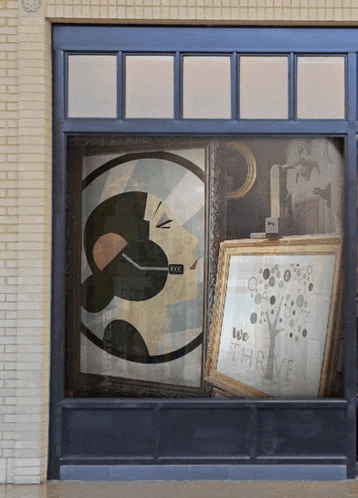 a window with a painting of a woman and the words we thrive