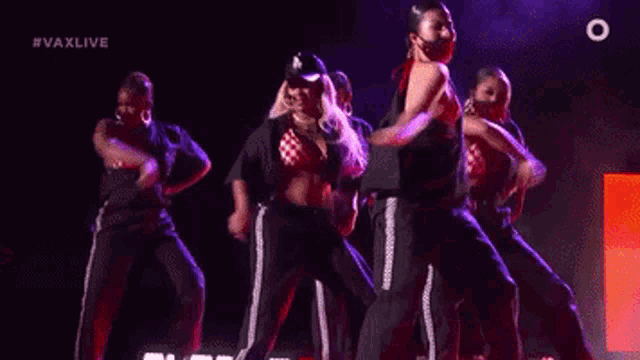 a group of dancers are performing on a stage with the hashtag #vaxlive