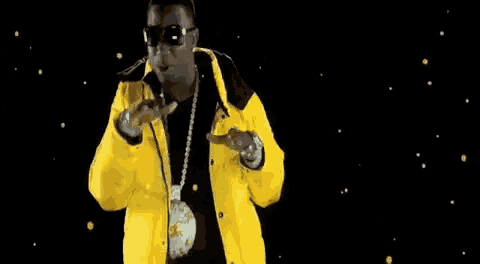 a man in a yellow jacket and sunglasses is wearing a gold medallion around his neck .