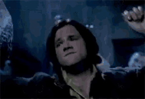 a man in a jacket is standing in a dark room with his arms outstretched .