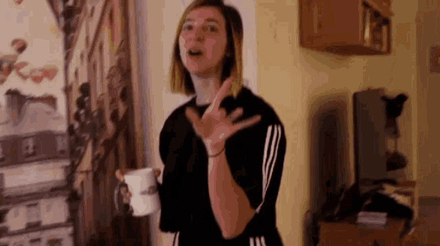 a woman is holding a cup of coffee and making a funny face .