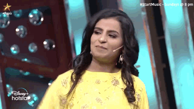a woman in a yellow dress is standing in front of a hotstar logo