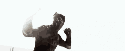 a black panther is standing on top of a building with his arms outstretched in a black and white photo .