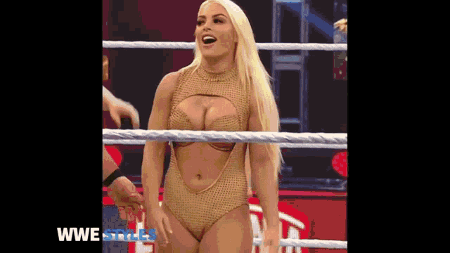 a woman is standing in a wrestling ring holding a man 's hand .