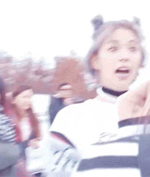 a woman with purple hair is making a funny face while wearing a choker and buns .