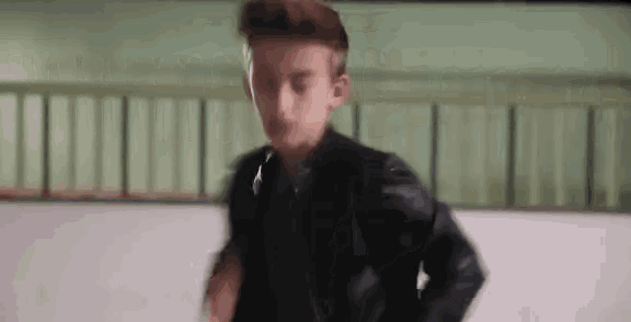a young man is wearing a black leather jacket and a black vest .