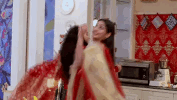 two women are dancing together in a kitchen .