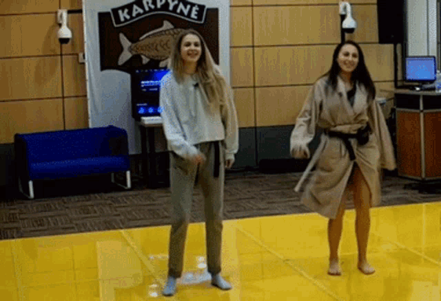 two women are dancing in front of a sign that says kardyne