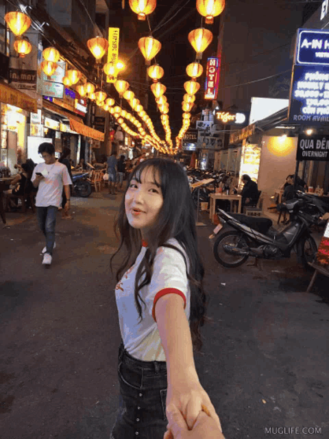 a girl is holding a man 's hand in front of a sign that says qua den overnight
