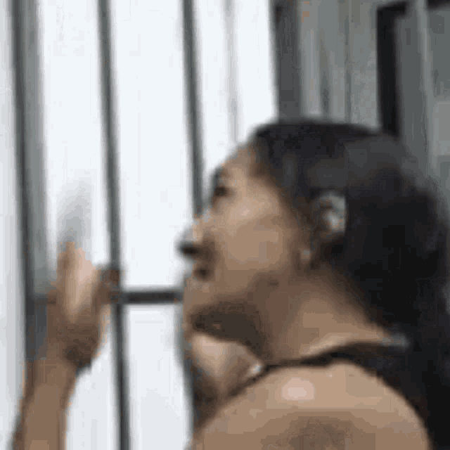 a woman is standing in front of a window with her hand on the window .
