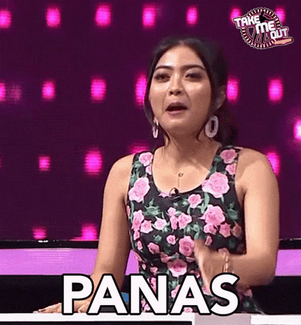 a woman in a floral dress is sitting at a table and says panas
