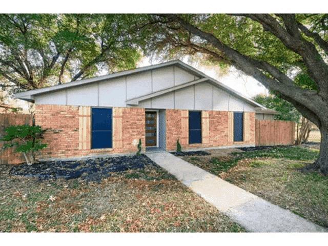 a brick house with a fence and a tree in front