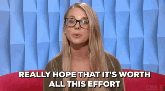 a woman with glasses is sitting on a red couch and saying really hope that it 's worth all this effort