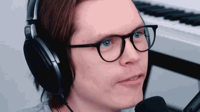 a man wearing glasses and headphones looks at the camera