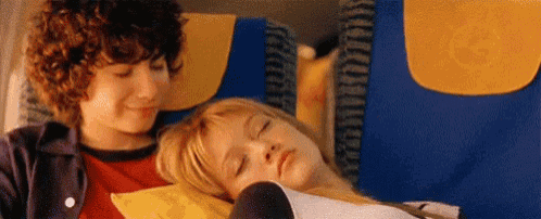 a boy and a girl are sitting next to each other on a plane .