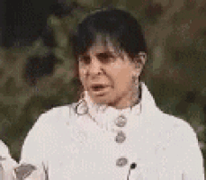 a woman wearing a white coat is making a funny face .