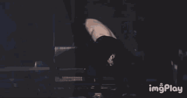 a blurry picture of a man dancing in a dark room with the words imgplay in the corner .