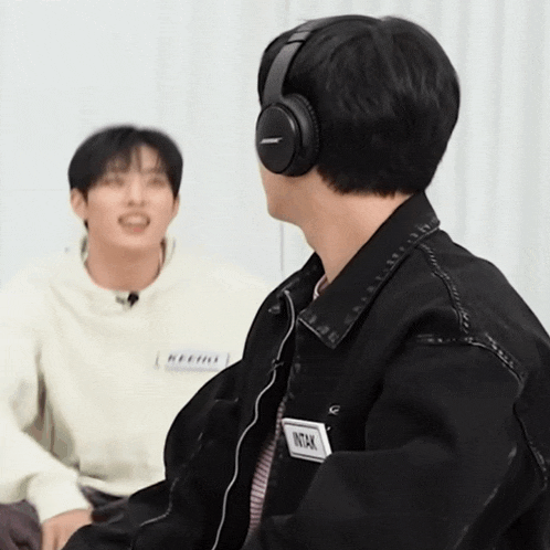a man wearing bose headphones has a name tag on his jacket that says intak