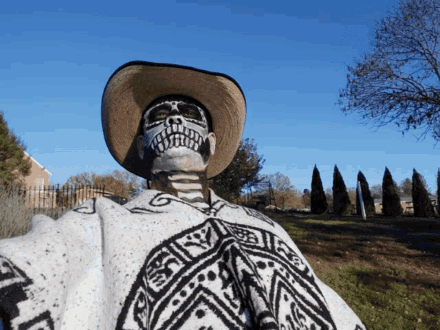 a man with a skeleton face painted on his face wearing a poncho