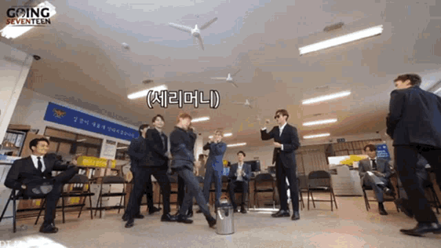 a group of men in suits are dancing in a room with a sign that says going seventeen on it