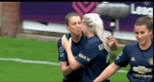 a woman in a kohler jersey hugging another woman on a soccer field