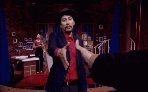 a man in a suit and hat is dancing in front of a sign that says tonight now .