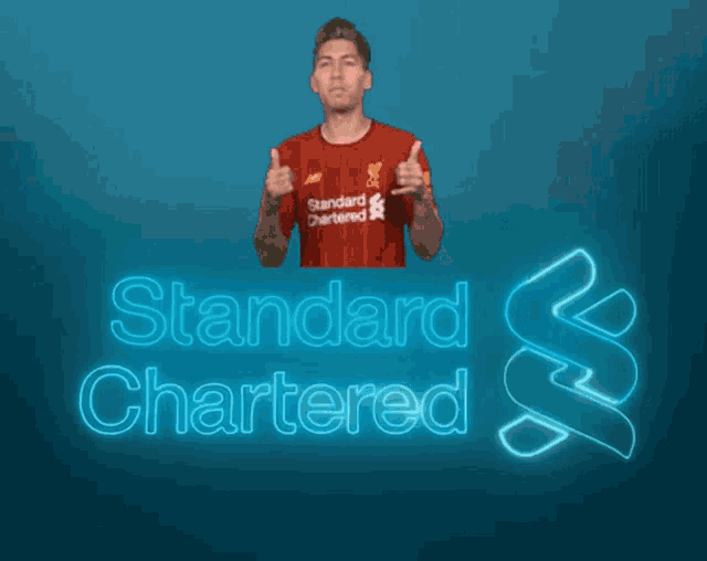 a man in a red shirt that says standard chartered gives a thumbs up