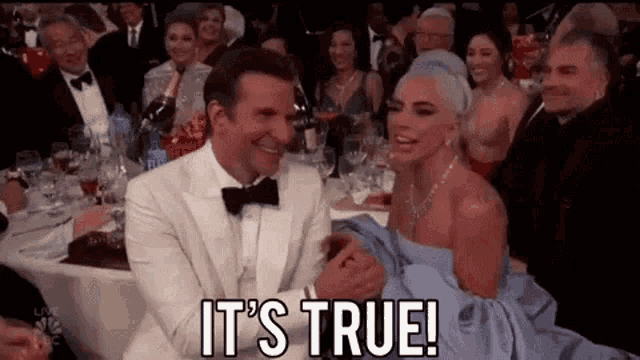 a man and a woman are sitting next to each other at a table at a party .