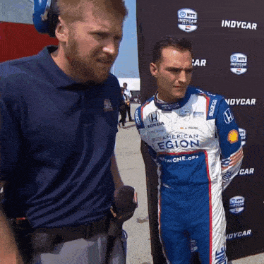 two men are standing in front of a sign that says indycar on it