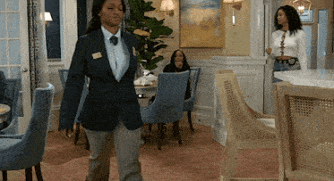 a woman in a suit and tie walks in a room