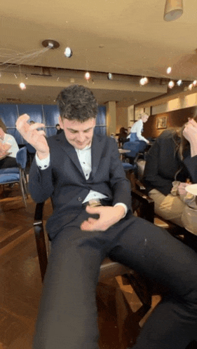 a man in a suit is sitting in a restaurant with his legs crossed